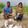 Rama Mishra and an assistant with a fishing cat in a fish-farming area in Sunsari district.