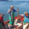 Christian Adams and Anthony Stofberg with their crew in a fishing boat.