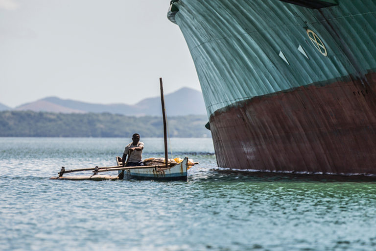 An artisanal fisherman next to a ship in Madagascar.