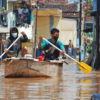 Residents paddle a boat down a flooded street in Bojongasih village.