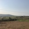 Wide shot of scattered buildings on green hills, a mountain on the horizon. Image by Victoria Schneider for Mongabay.