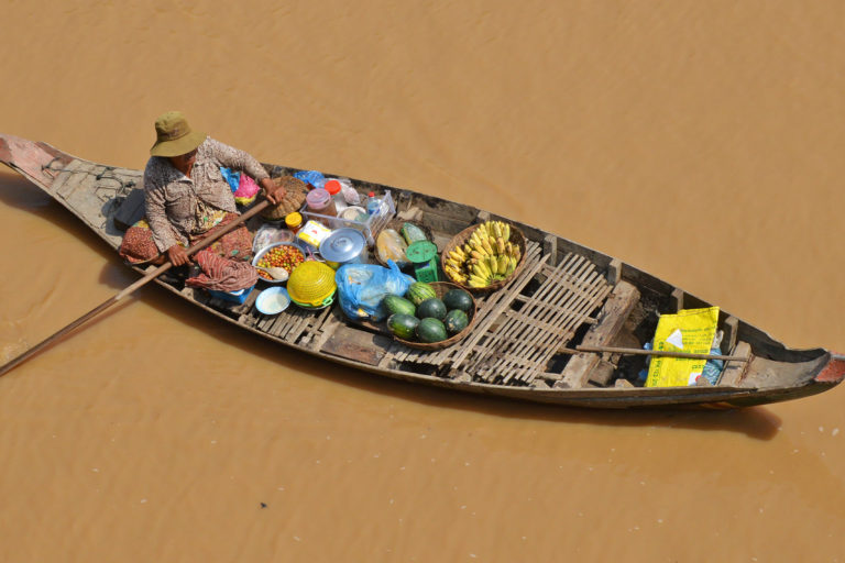 Woman paddling a boat loaded with fruit to sell.